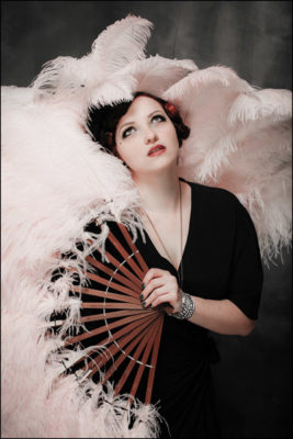 Ruby Bordeaux of Missoula's Cigarette Girls Burlesque Troupe with large pink fan.