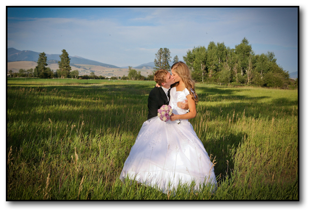 Groom kissing the bride in vast beautiful Western Montana Landscape on a sunny day.